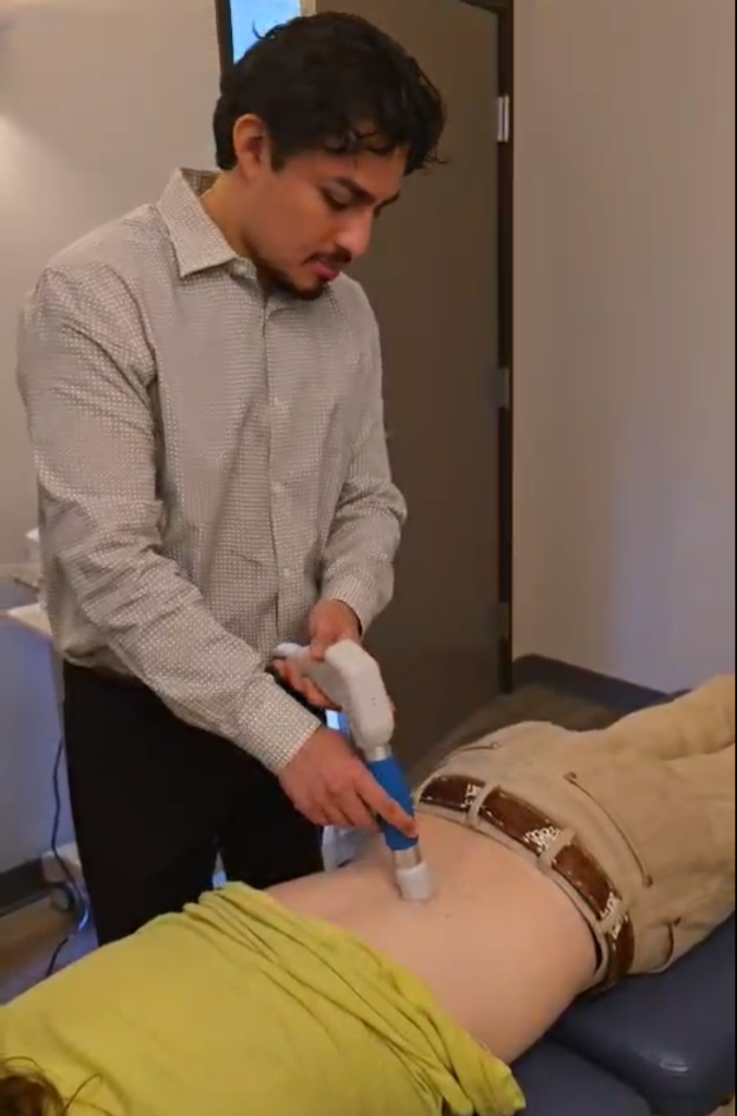 Image of a therapy assistant utilizing Shockwave Therapy to help with low back pain in Plano, TX